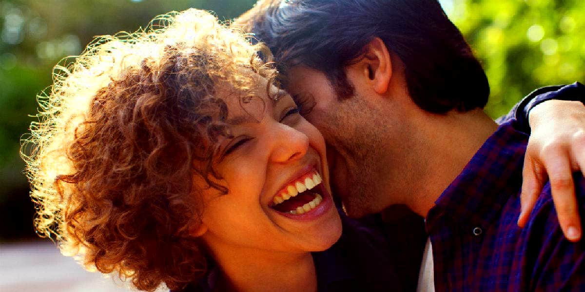 woman smiling while she hugs her boyfriend