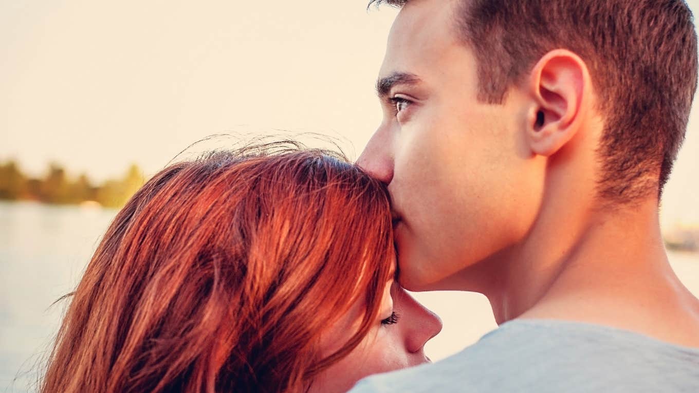 man kissing woman's forehead