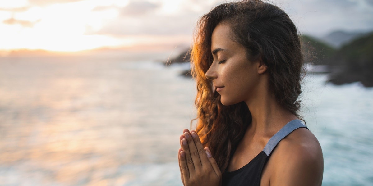 woman meditating on beach