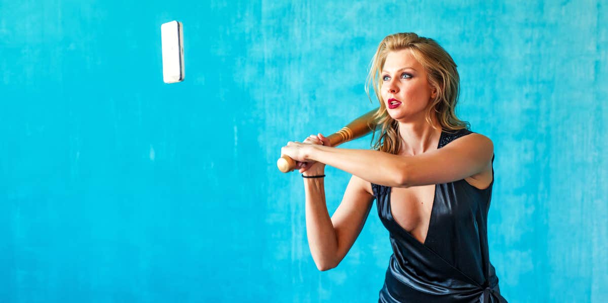 woman with baseball bat swinging at cell phone in the air