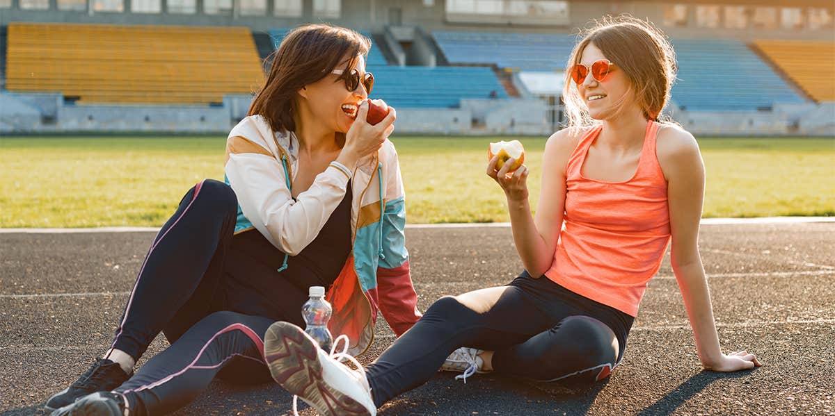 two women eating apples on track