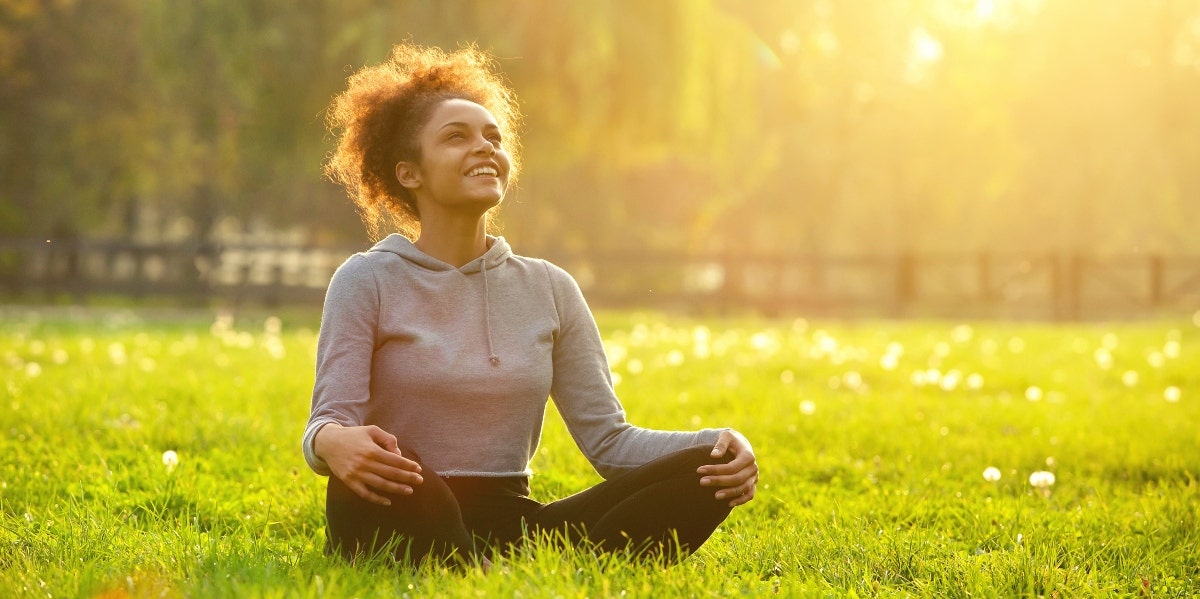 smiling woman meditating outside in the sun