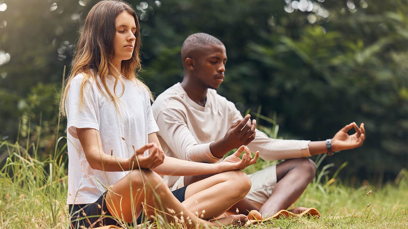 couple meditating together in grass