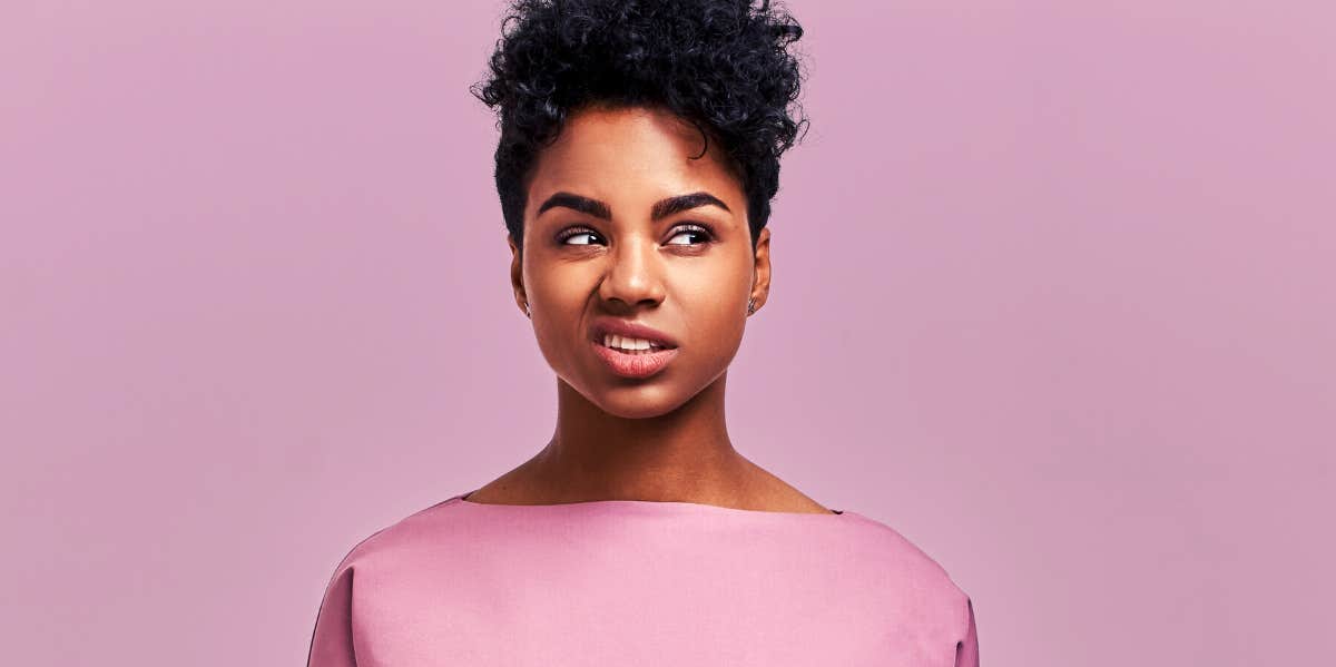 annoyed woman rolling her eyes in front of pink background