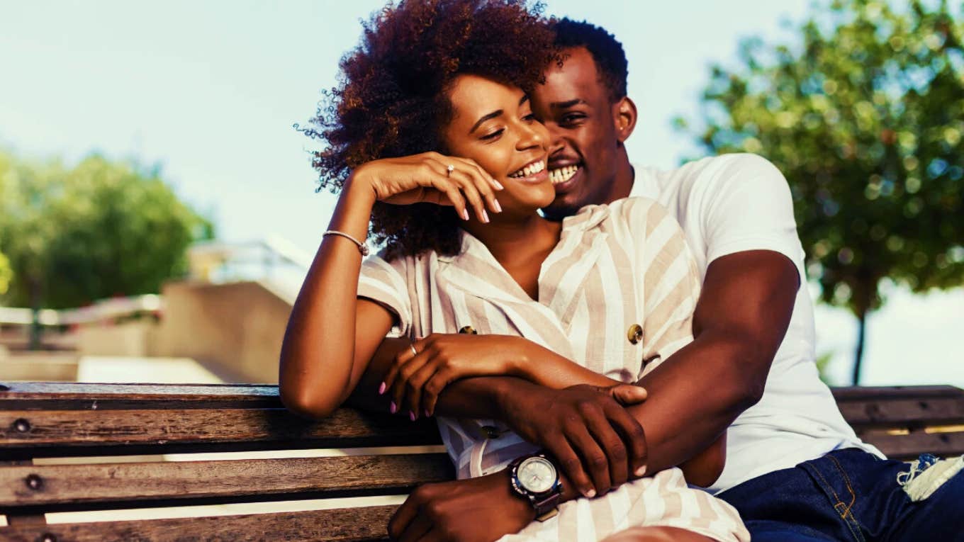 happy couple sitting on a bench hugging