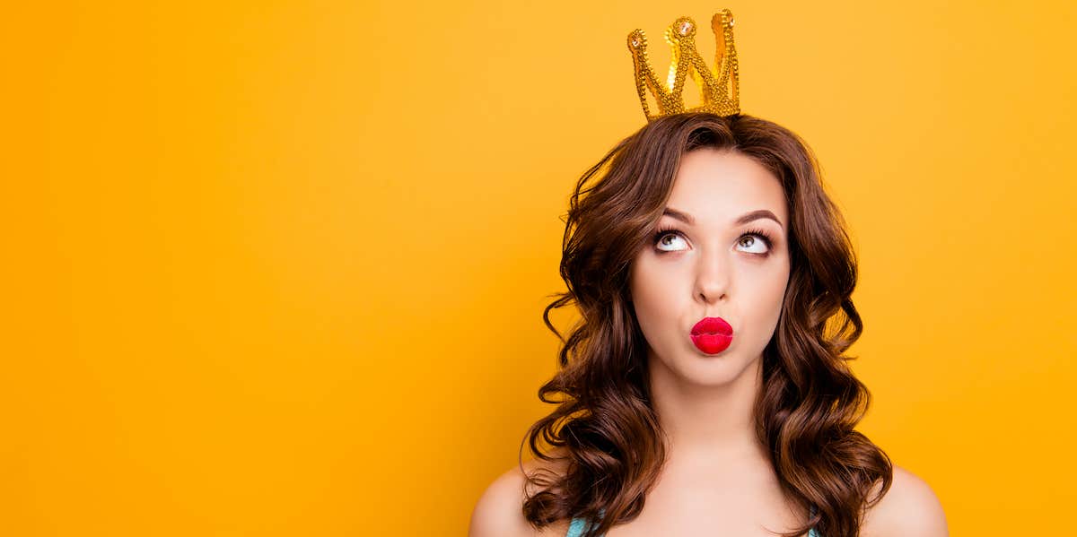 A vain woman wearing a crown rolls her eyes and purses her lips against a bright yellow background