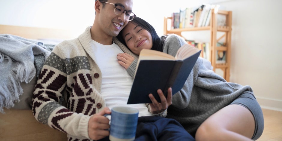man and woman reading together on couch