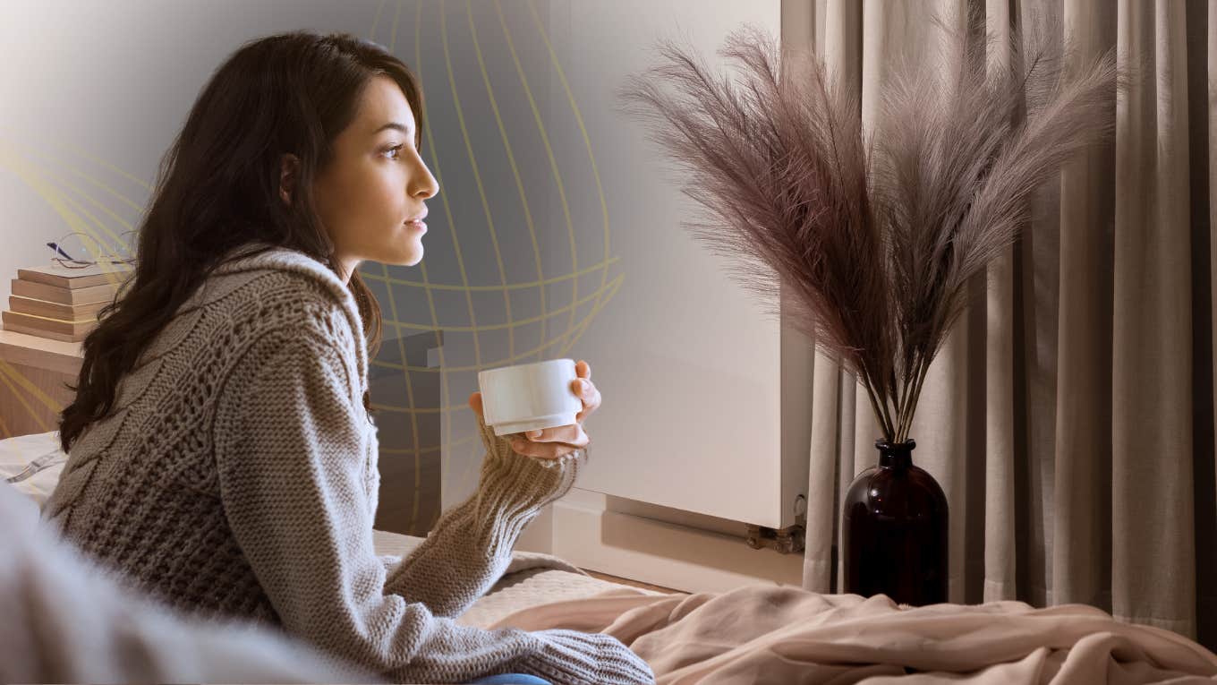 female reflecting out window with coffee in her cup