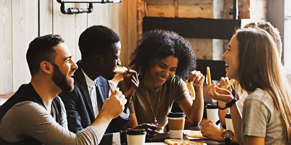 racially diverse group of adults talking over pizza dinner