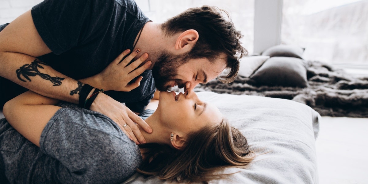 How The Zodiac Signs Kiss And What It Means For Each man and woman laying on a bed kissing