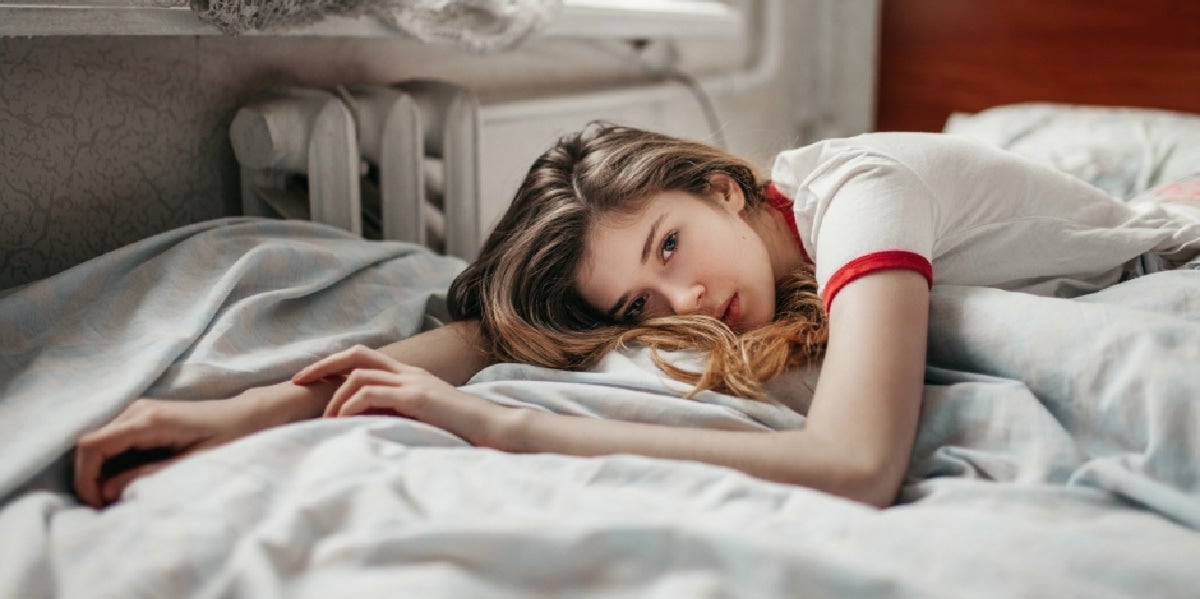 woman laying on bed upset sad