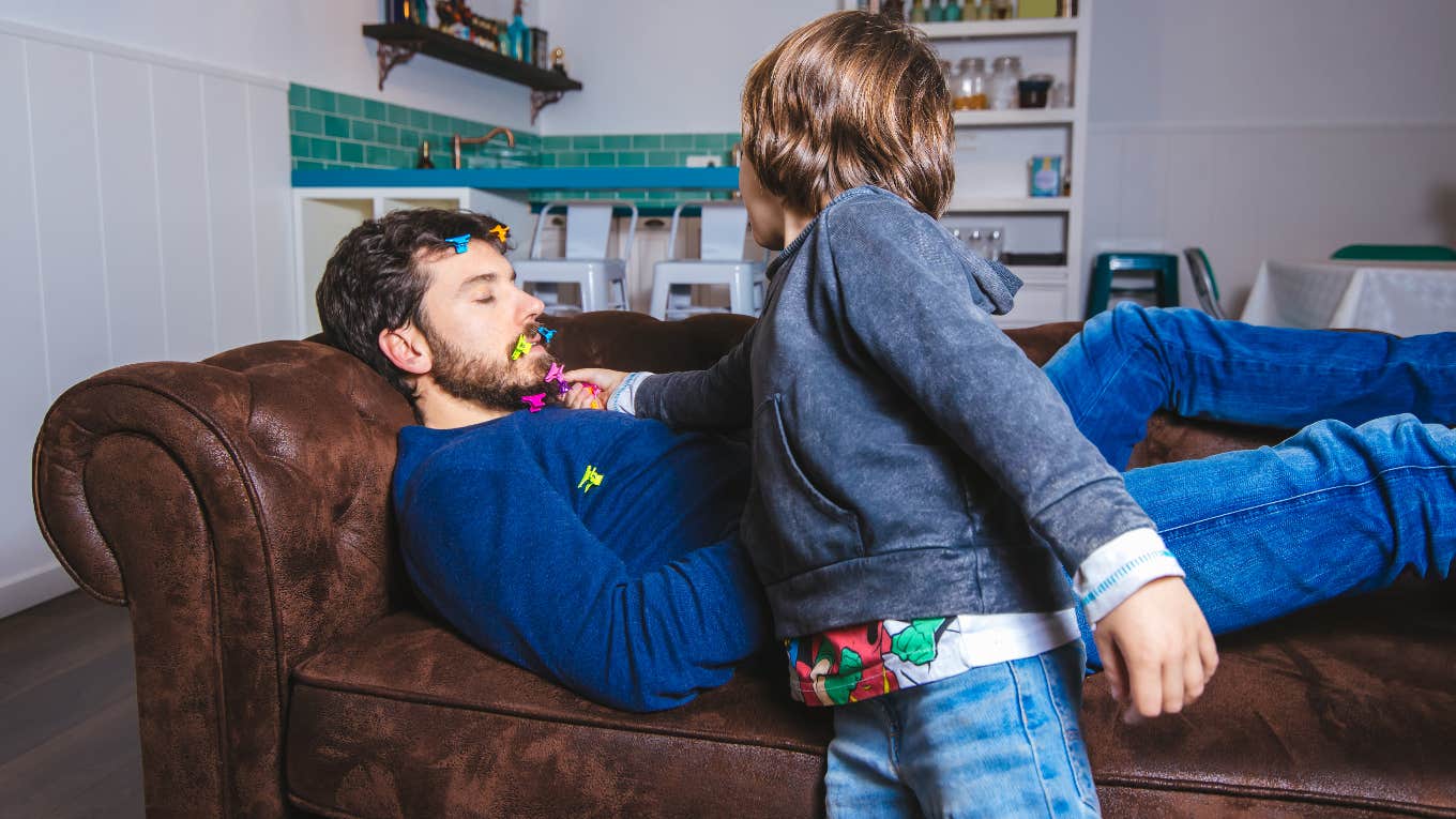 young boy playing with dad sleeping on the couch