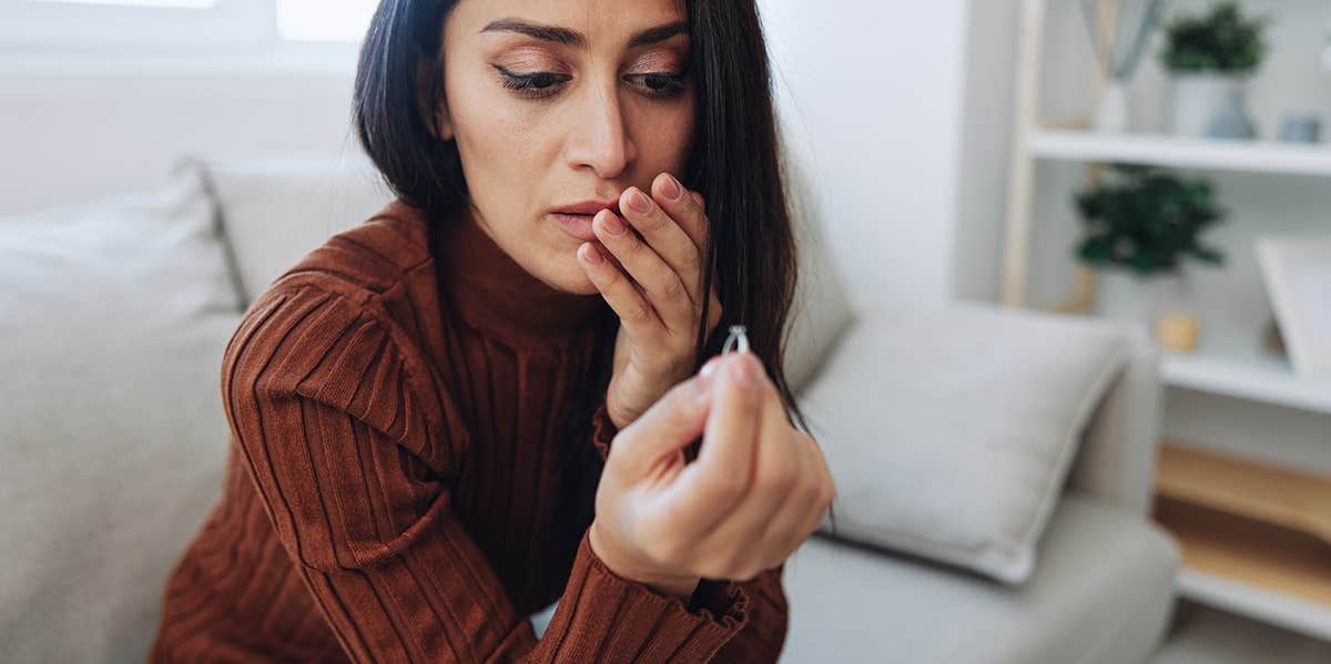 sad woman holding husband ring