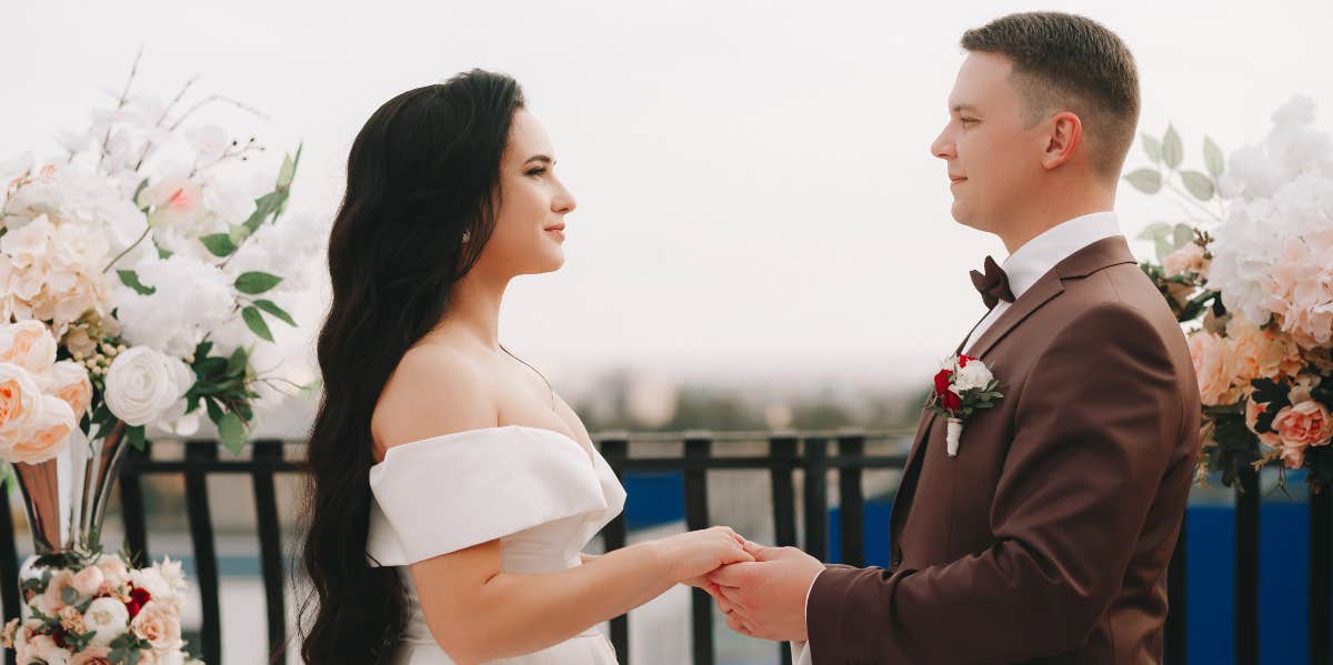 Groom Surprises Bride With Vows That Her Family Understands bride and groom holding hands during wedding ceremony