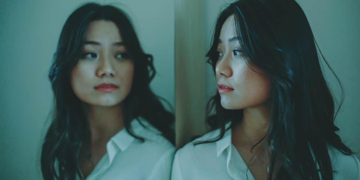 Young woman looking at her reflection in a mirror