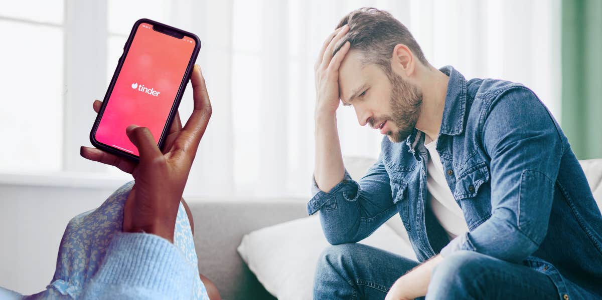 woman holding phone with tinder app open, upset man