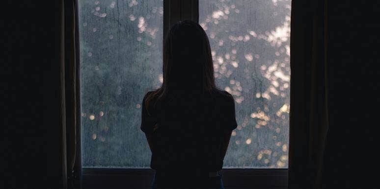 woman in dark looking out window