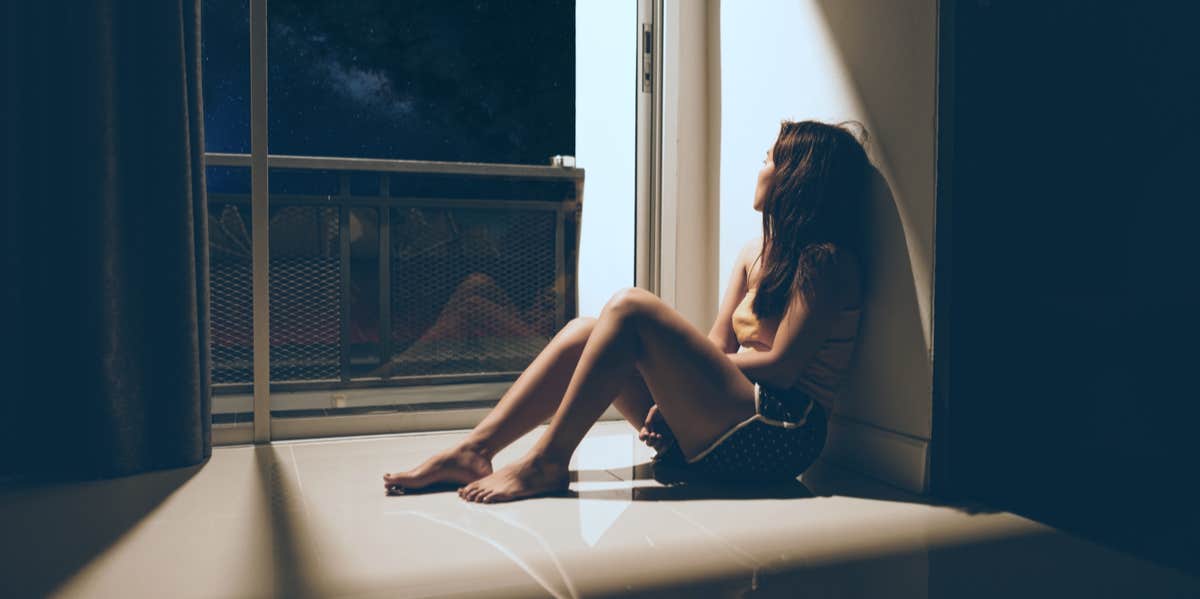 woman sitting on the floor looking out window