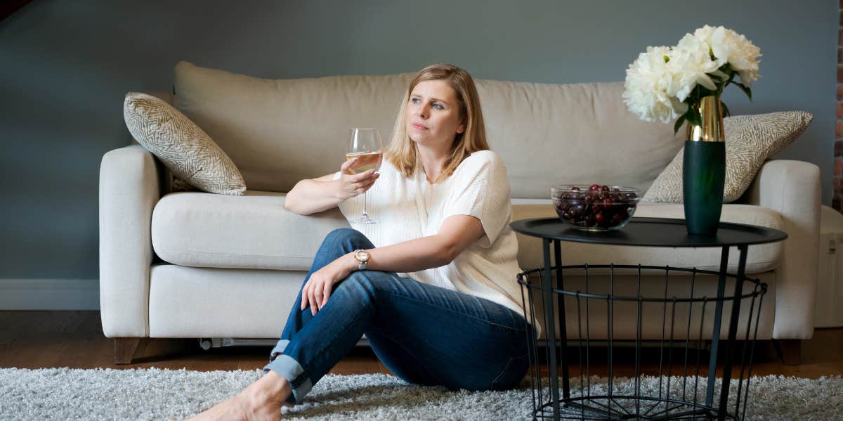 mother on living room floor drinking wine