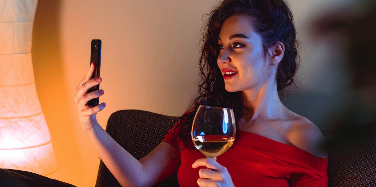 woman drinking wine while video chatting on phone