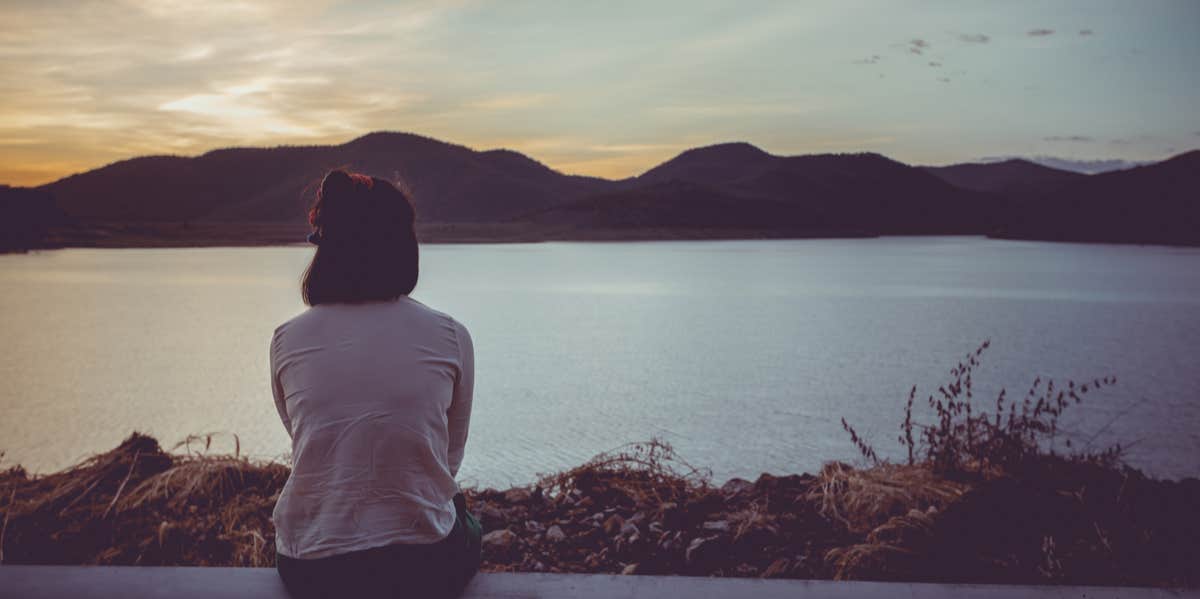 woman sitting by lake