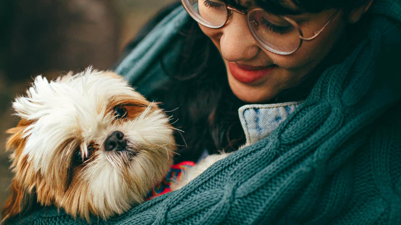 Woman holding her Shih Tzu crying 