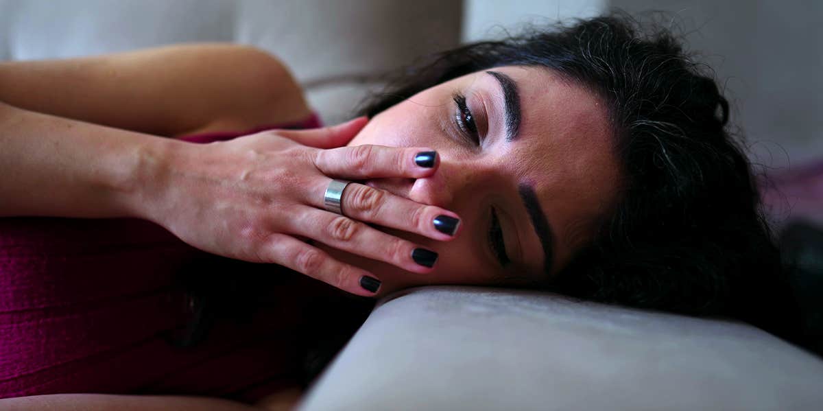 girl laying in bed with hand over mouth