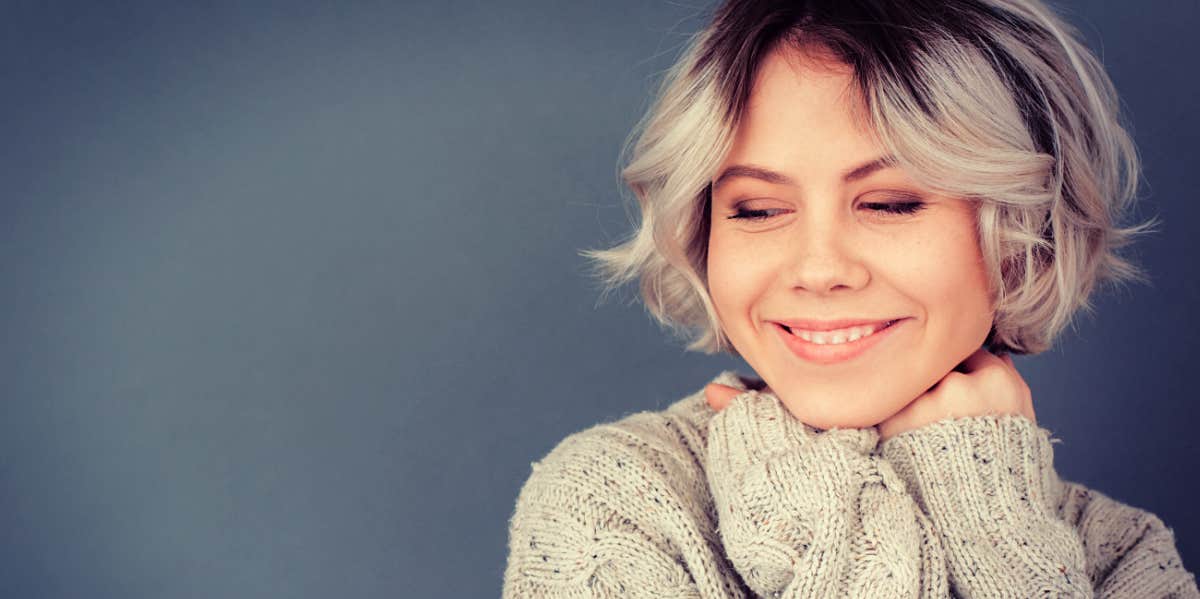 young woman smiling peacefully on a grey background