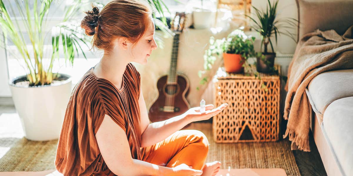 girl sitting on floor at home holding crystal