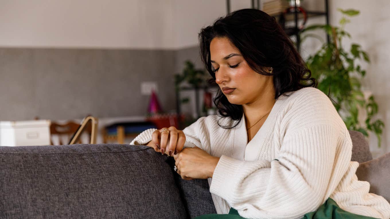 Sad woman playing with her hands on the couch 