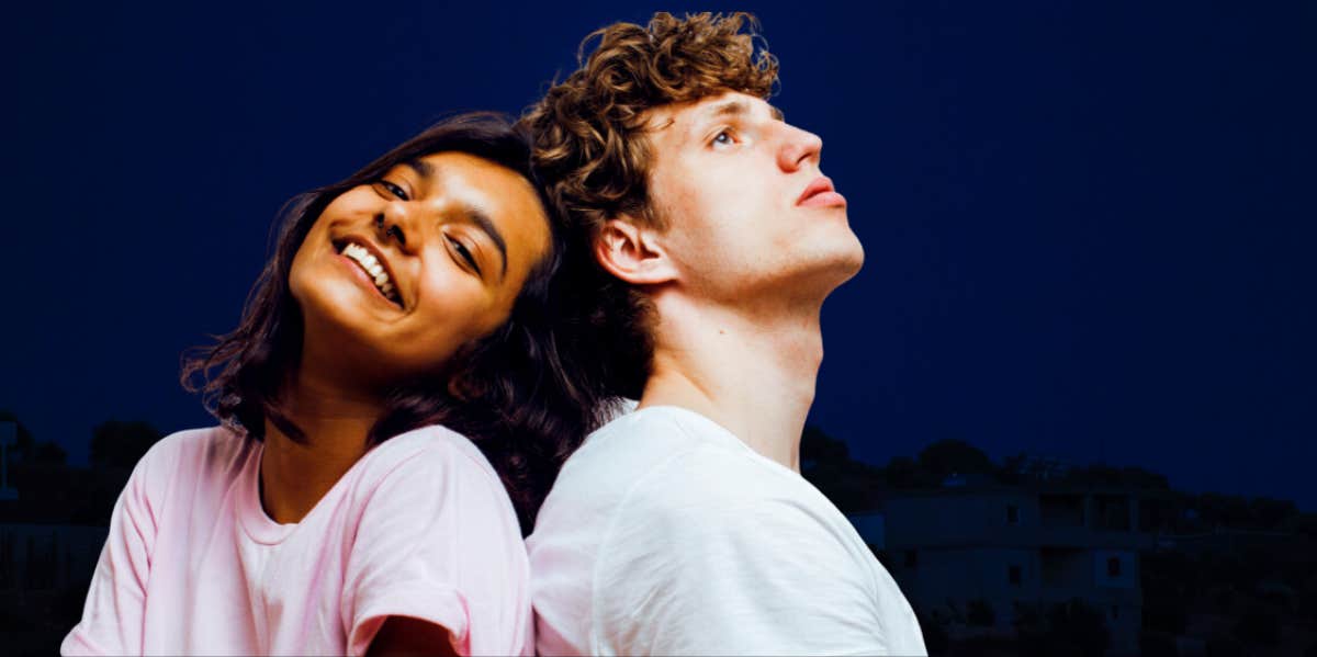 couple back-to-back looking up at the sky, against a black background