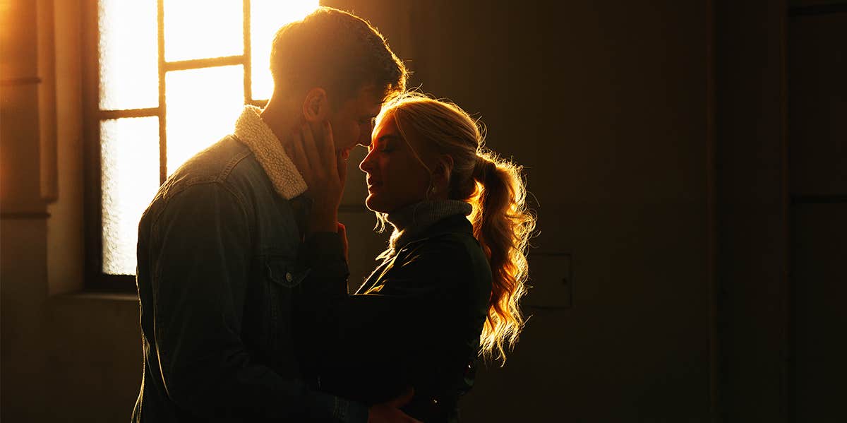 If Your Relationship Has These Traits, It's Practically Unshakeable man and woman hugging with sunlight behind them through window