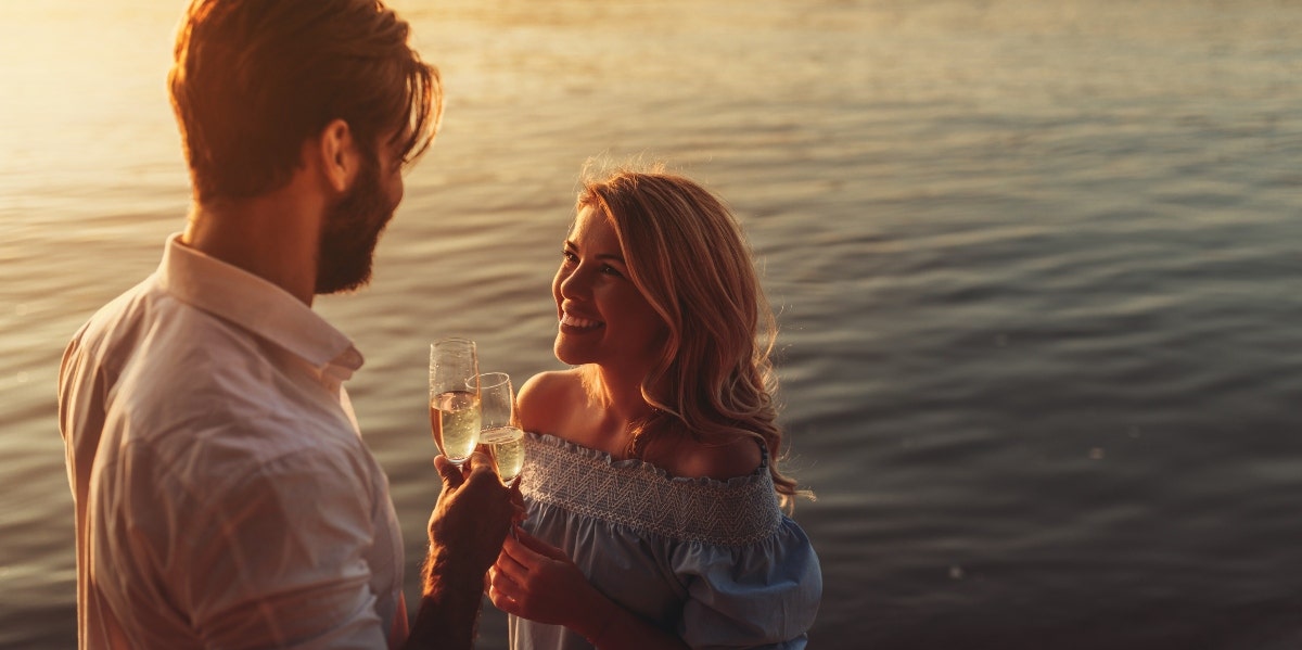 man and woman sharing a drink by the water