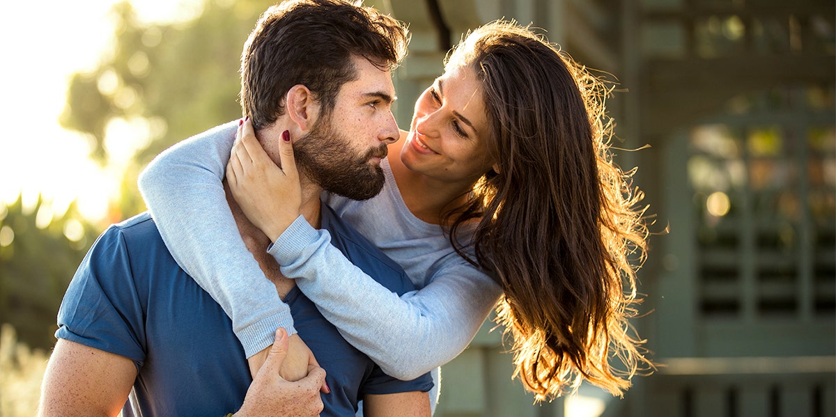 woman with arms around man's neck hugging from behind