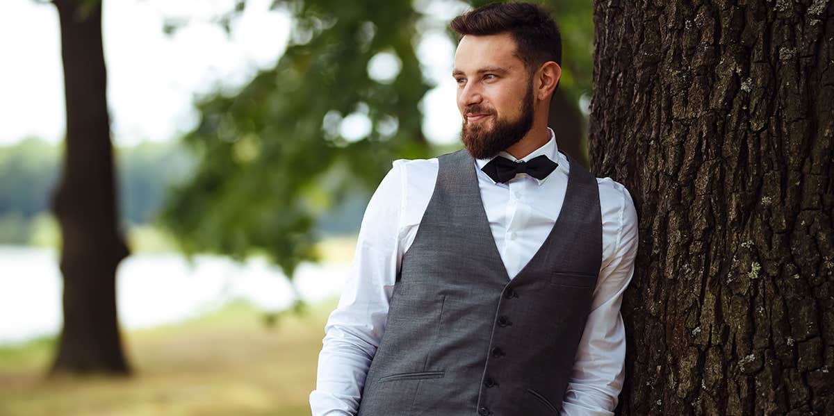 groom posing by tree