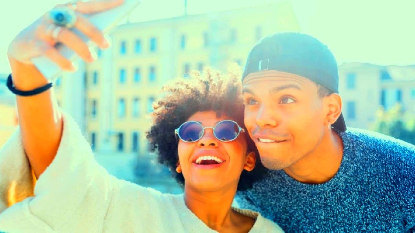 woman taking selfie with a man who is using her for an ego boost
