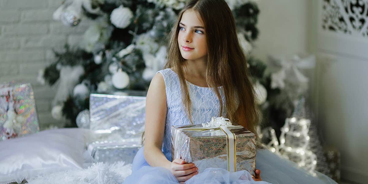 teen girl sitting by christmas tree