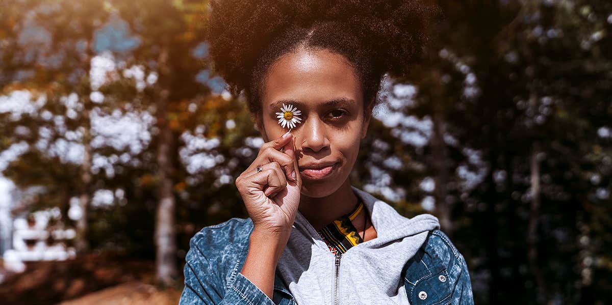 woman holding flower in front of eye