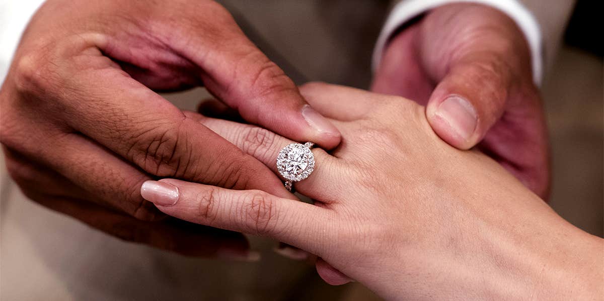 man putting engagement ring on woman's finger