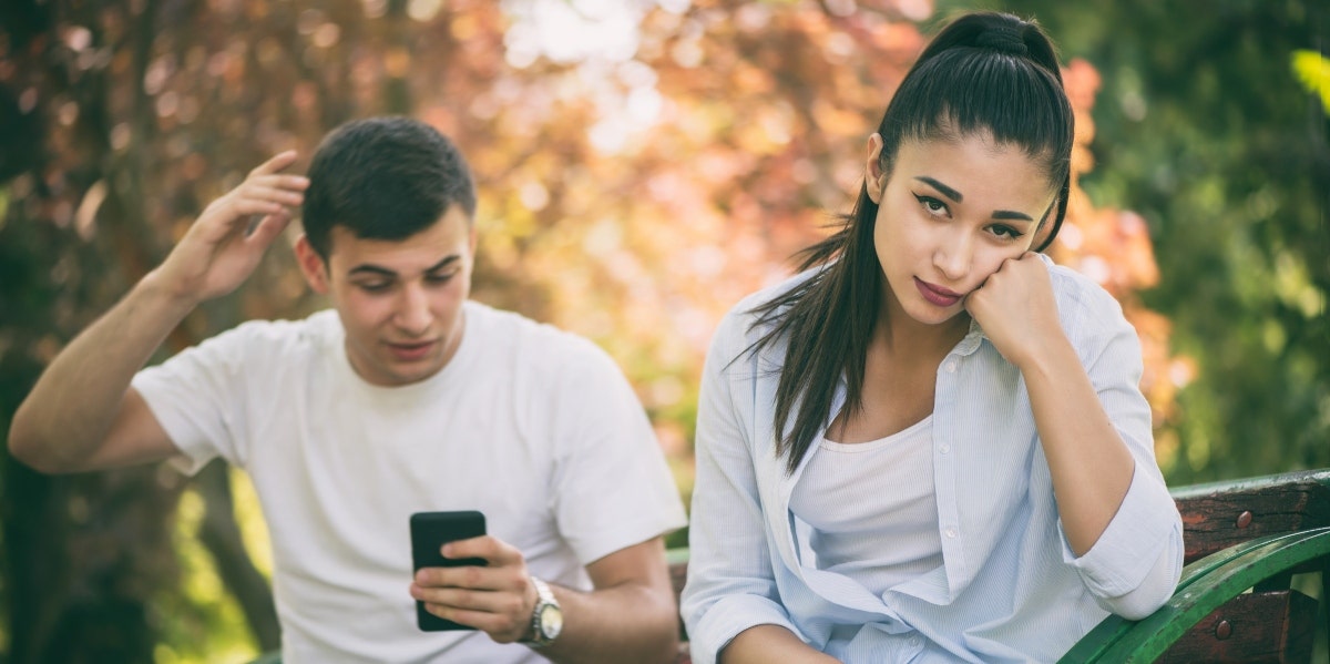 upset woman with man behind her on his phone