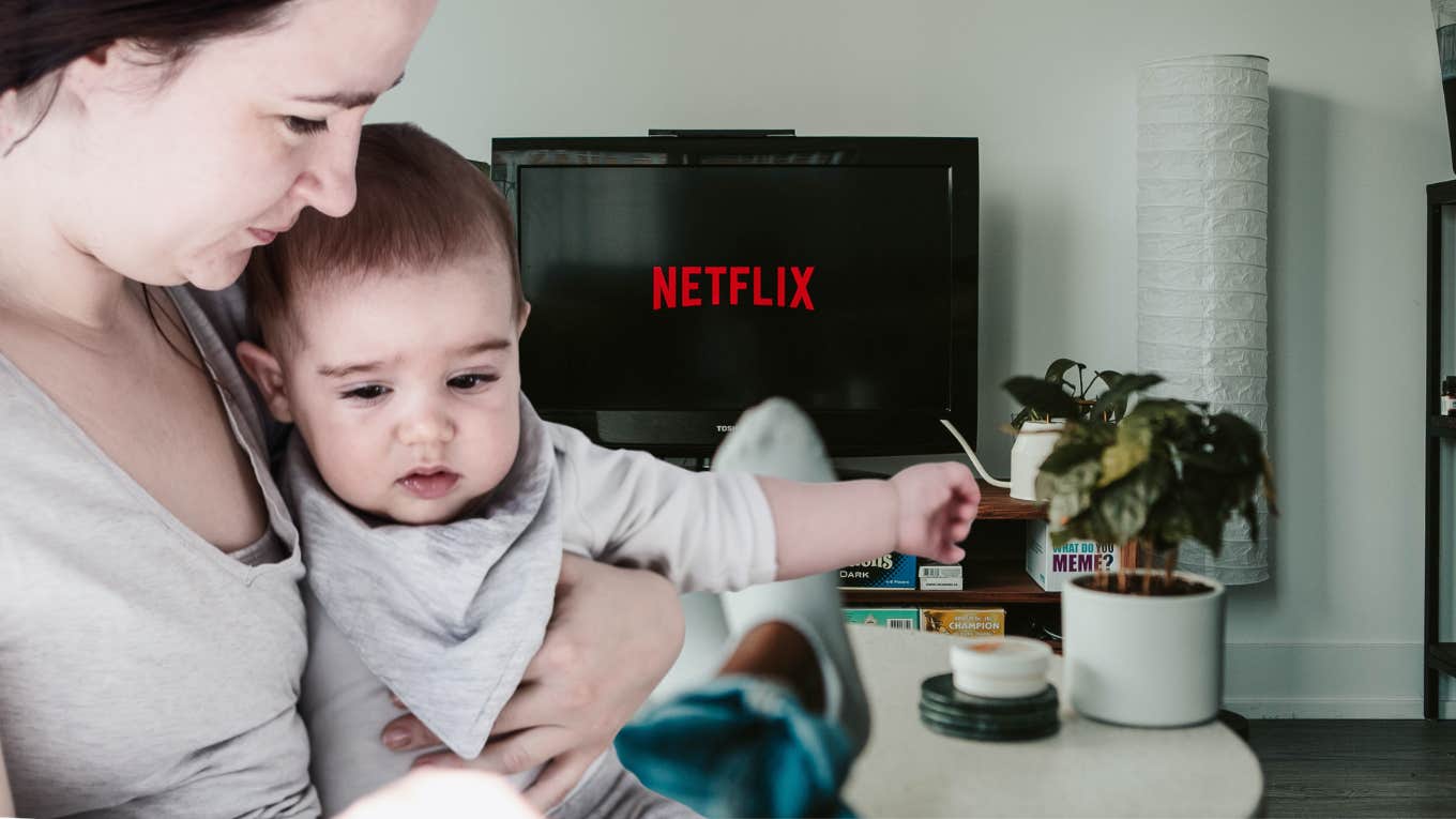 woman holding baby and man watching netflix