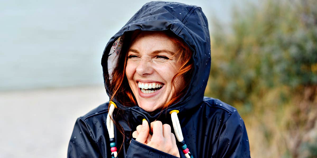 5 Ways Successful People Stay Calm In Chaos redhead woman with freckles laughing in raincoat