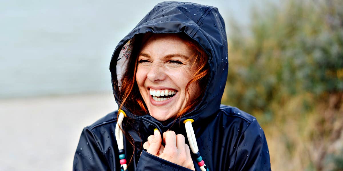 redhead woman with freckles laughing in raincoat