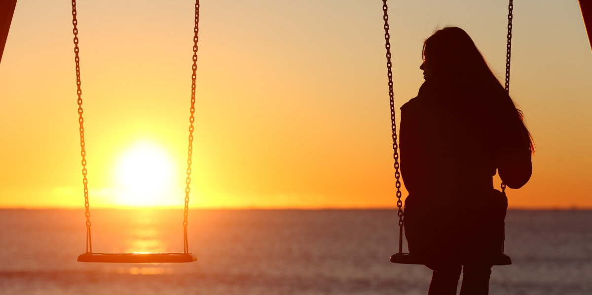 woman on swingset with sunset