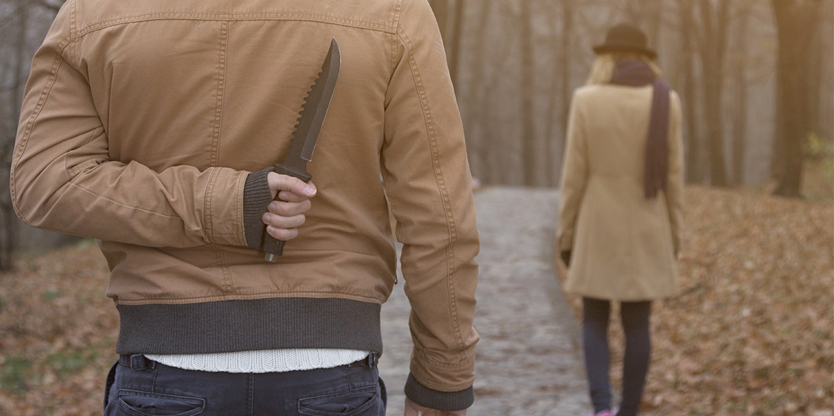 What Makes Someone Become A Serial Killer man standing behind a woman with a knife behind his back