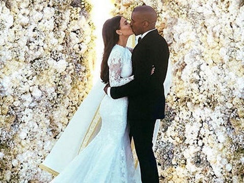 Kim Kardashian and Kanye West kissing at their wedding in front of a wall of roses, from Kardashian's Instagram account