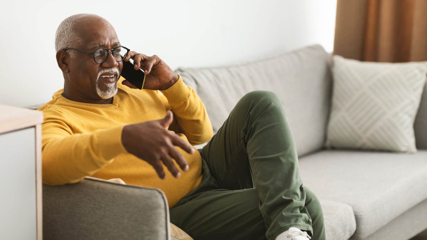man sitting on couch while speaking on the phone