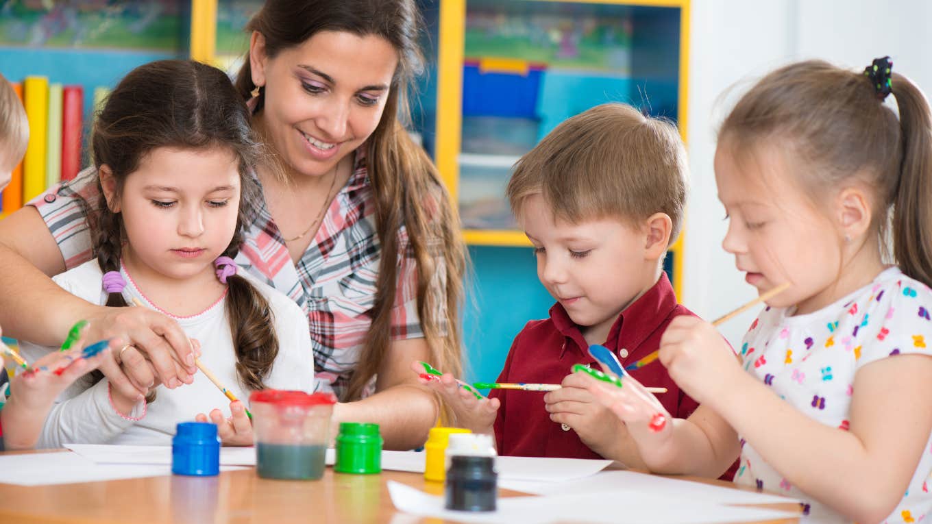 children drawing with teacher in class