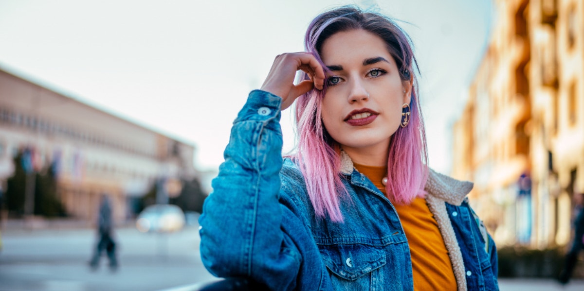 woman with pink hair smiling with hand on head