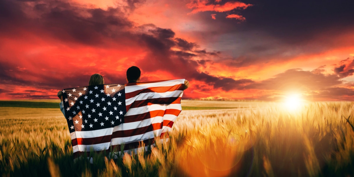 couple holding American flag watching sunset